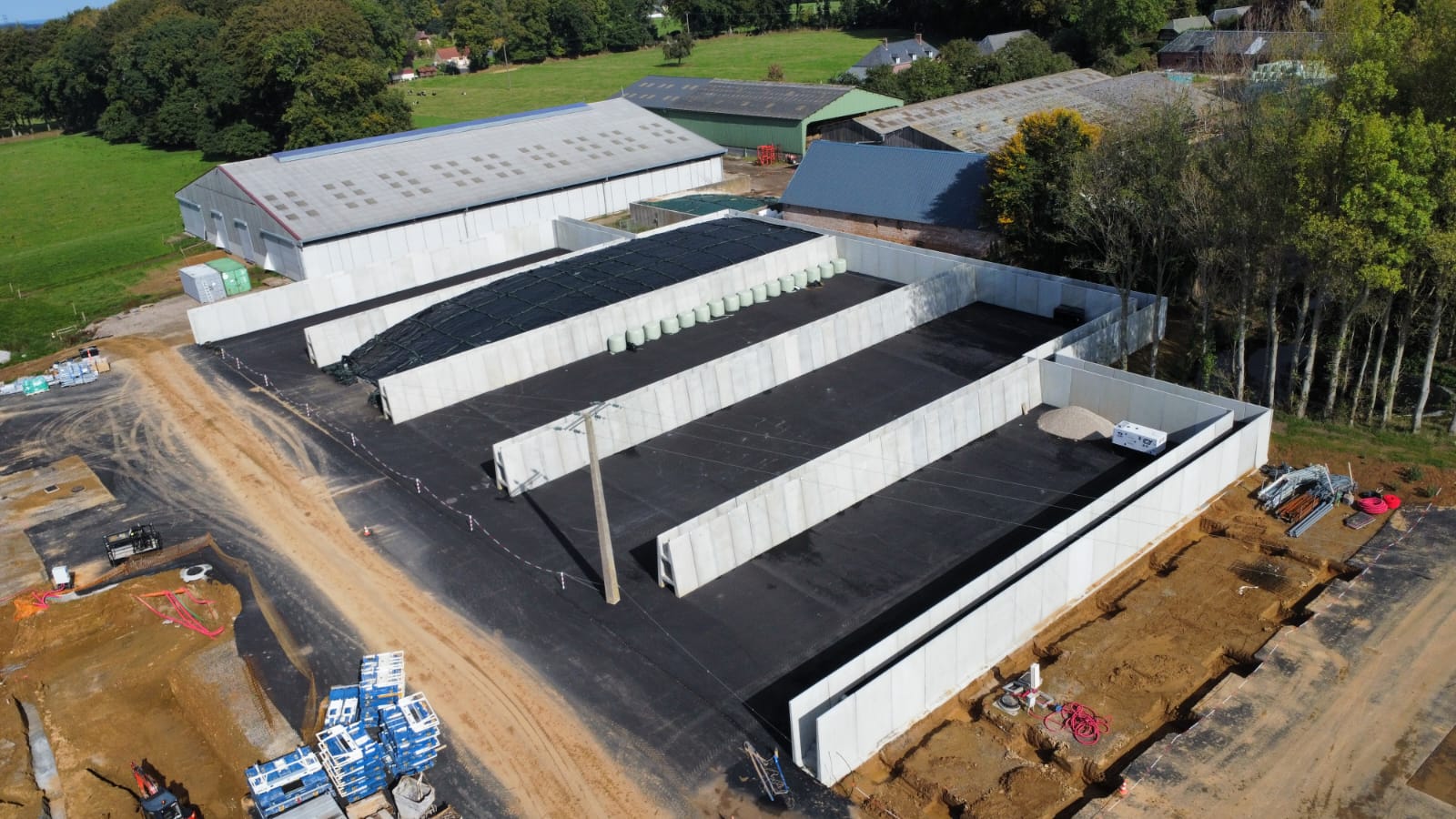 Chantier terrassement avec murs en béton préfabriqué sur sol asphalté en Normandie