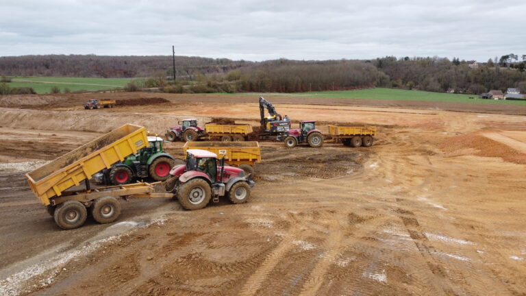 Chantier de terrassement en Normandie avec tracteurs et pelleteuse en action sur terrain découvert