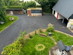 Cour asphaltée entourée de pelouse et bâtiments vue du dessus